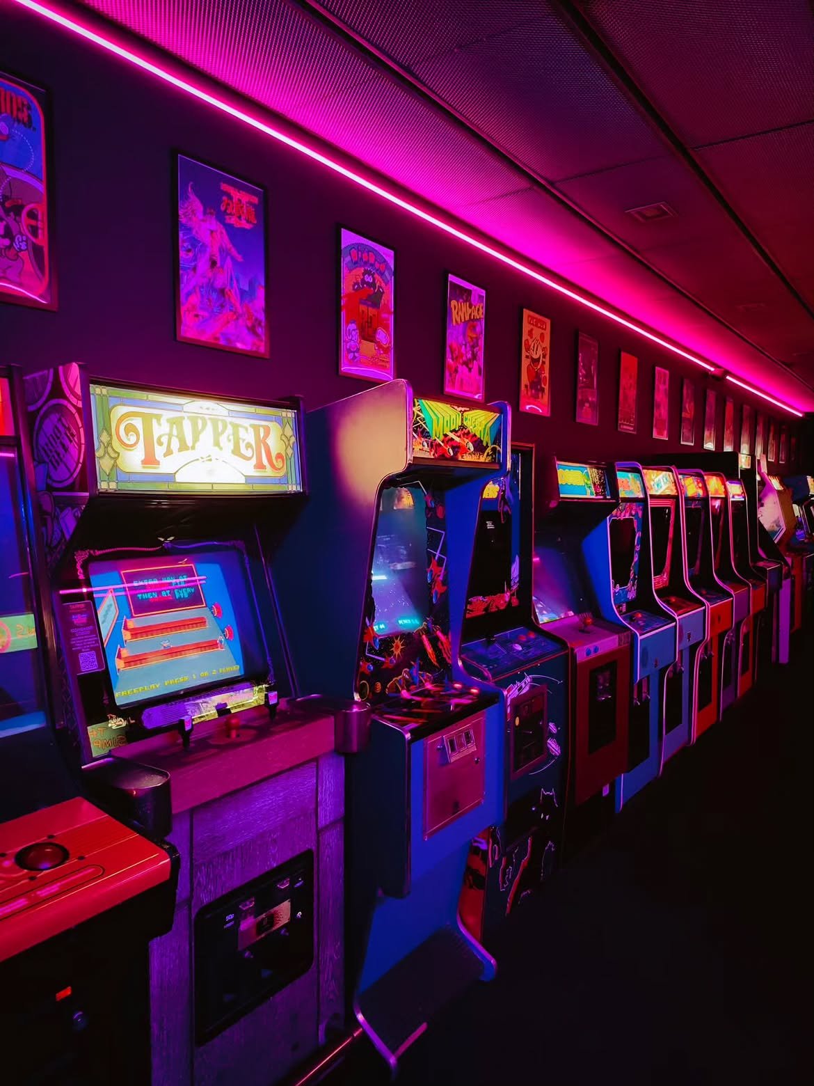Fila de máquinas arcade clásicas iluminadas en Arcade Planet Sevilla